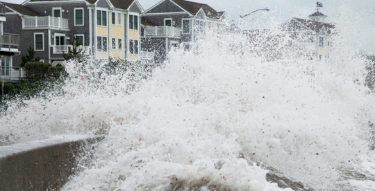 ocean storm surge with homes in the background
